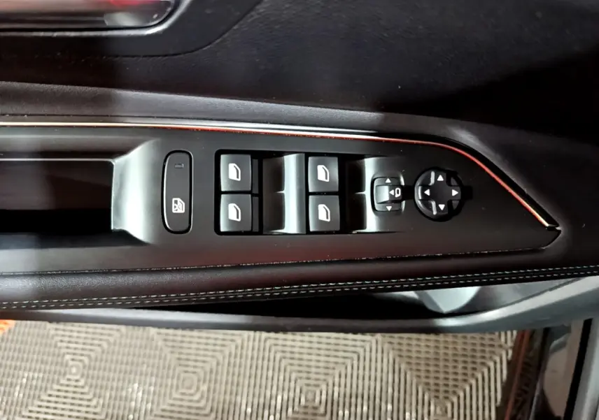 Gros plan sur les commandes de lève-vitres et rétroviseurs côté gauche, avec finition cuir noir et surpiqûres blanches.