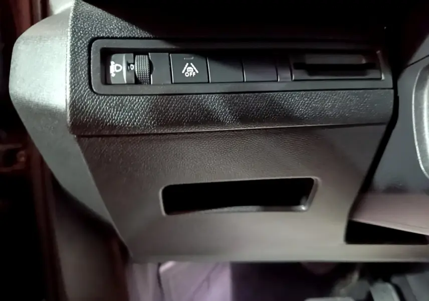 Gros plan sur les commandes d’éclairage et d’aide à la conduite côté gauche du tableau de bord noir du Peugeot 3008 2022.
