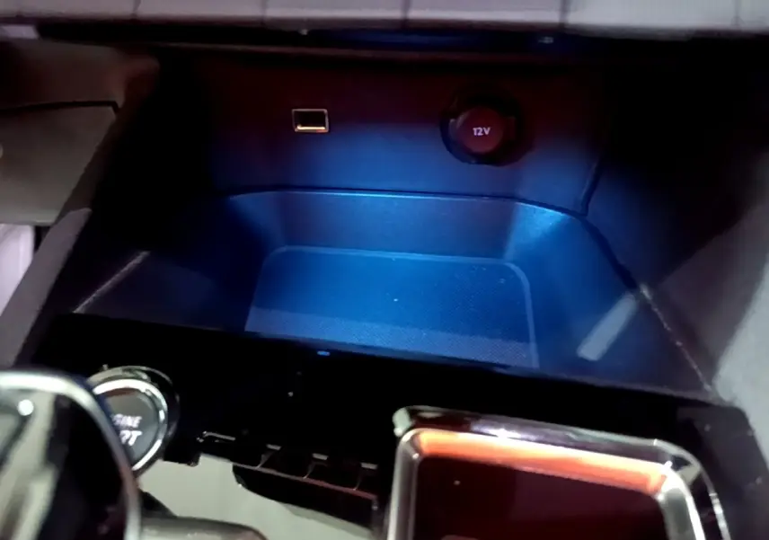 Gros plan sur la prise 12V et port USB dans le rangement central du Peugeot 3008 noir, version 2022.