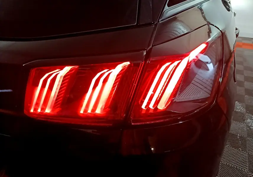 Gros plan sur le feu arrière droit allumé d’un Peugeot 3008 noir, soulignant son design LED distinctif.