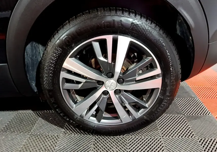 Gros plan sur la roue avant droite du Peugeot 3008 noir, jante alliage argentée à design moderne.