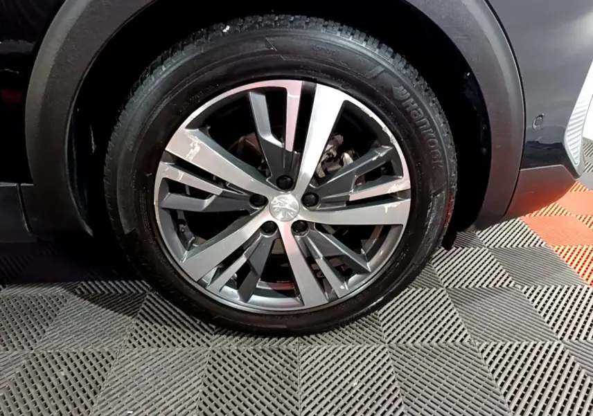 Gros plan sur la roue avant droite du Peugeot 3008 noir, avec jante alliage à design moderne et pneu Hankook.