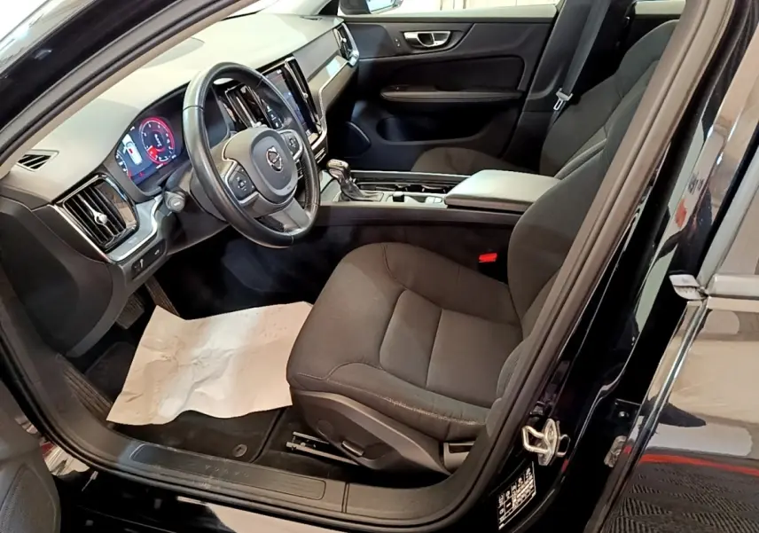 Intérieur avant droit de la Volvo V60 noire 2020, montrant siège conducteur, volant cuir et tableau de bord digital.