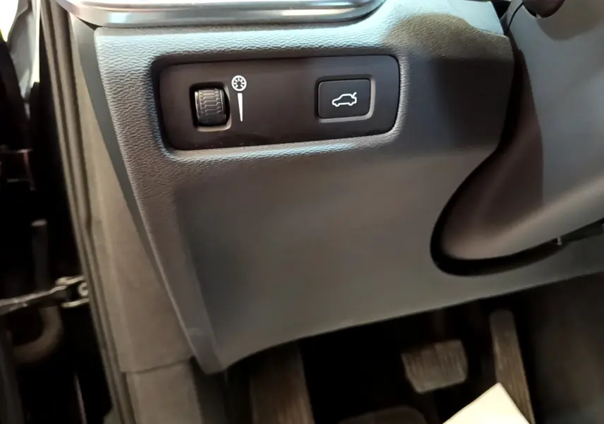 Gros plan sur commandes d'ouverture de coffre et réglage tableau de bord côté conducteur dans Volvo V60 noir 2020.