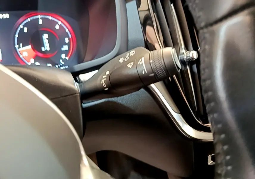 Détail du commodo d’essuie-glace côté gauche avec tableau de bord numérique rouge et noir d’une Volvo V60 2020.