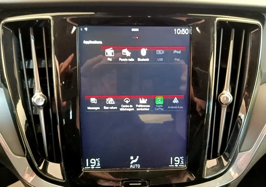 Écran tactile central allumé encadré par deux aérateurs verticaux dans l’habitacle noir d’un Volvo V60.