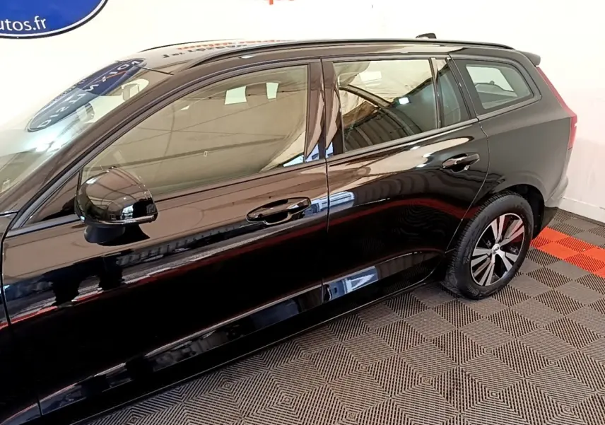 Vue de profil côté gauche d'un Volvo V60 noir brillant avec jantes alliage et rétroviseurs électriques.
