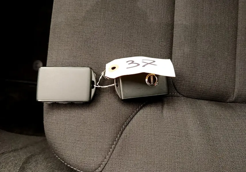 Clé de voiture Volvo V60 D3 noire posée sur un siège tissu gris foncé, vue rapprochée intérieure.