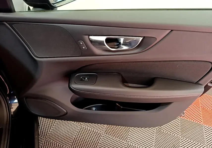 Vue rapprochée de la porte avant gauche noire du Volvo V60 2020, avec poignée chrome et commandes de verrouillage.