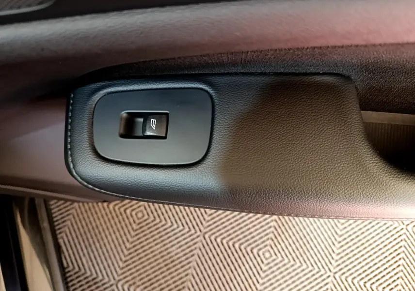 Gros plan sur le bouton de commande de la vitre électrique côté conducteur d’une Volvo V60 noire de 2020.