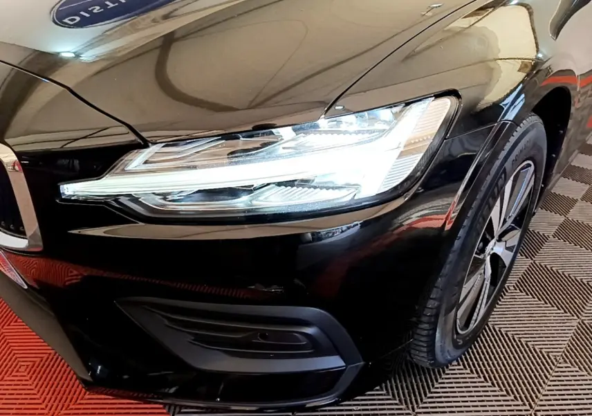 Gros plan sur l'avant droit noir d'une Volvo V60 2020, mettant en valeur le phare LED et la jante alliage.