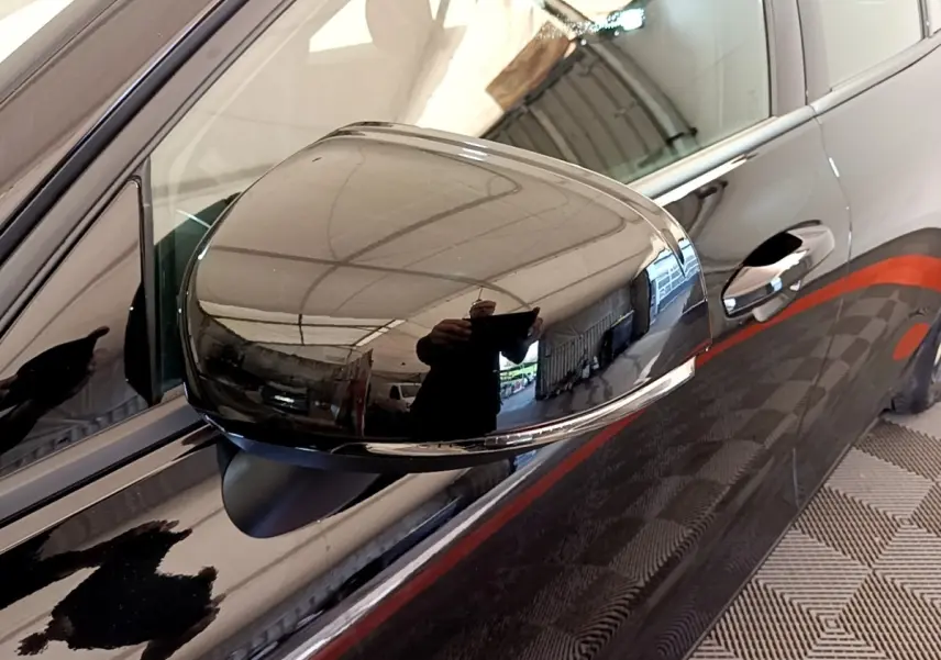 Rétroviseur côté gauche noir brillant d'une Volvo V60 D3 Business 2020 avec poignée de porte et carrosserie noire en reflet.