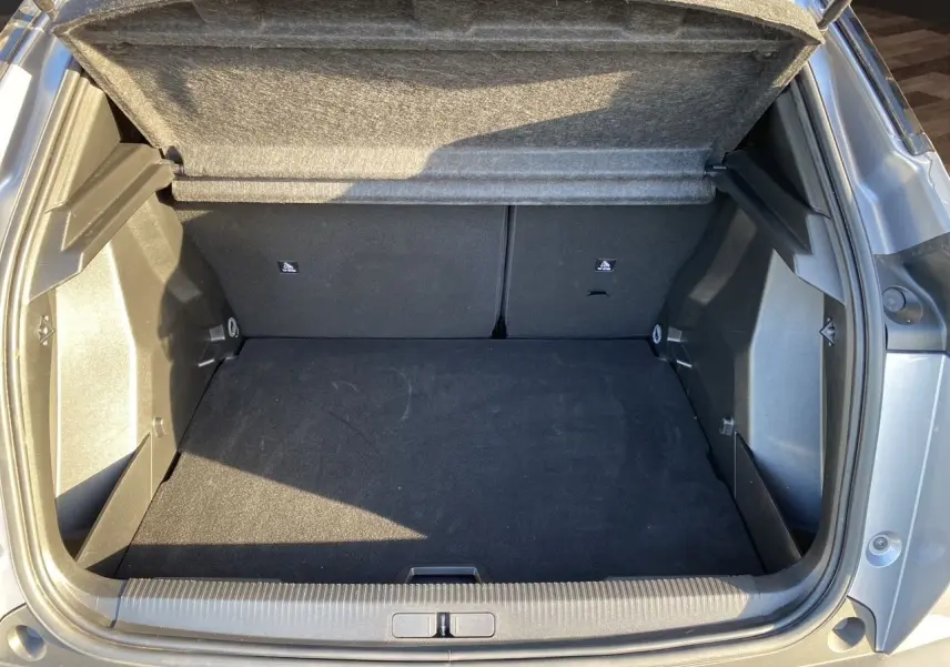 Coffre ouvert en vue arrière d'un Peugeot 2008 gris Artense, montrant un espace de chargement propre et spacieux.