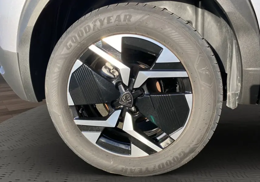Gros plan sur la roue avant gauche du Peugeot 2008 gris Artense avec jante alliage noire et argentée design moderne.