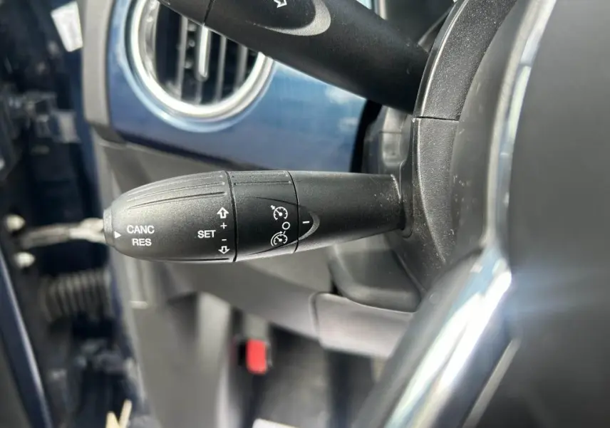 Gros plan sur la commande de régulateur de vitesse noire dans l'habitacle bleu d'une Fiat 500 2024 Dolcevita.