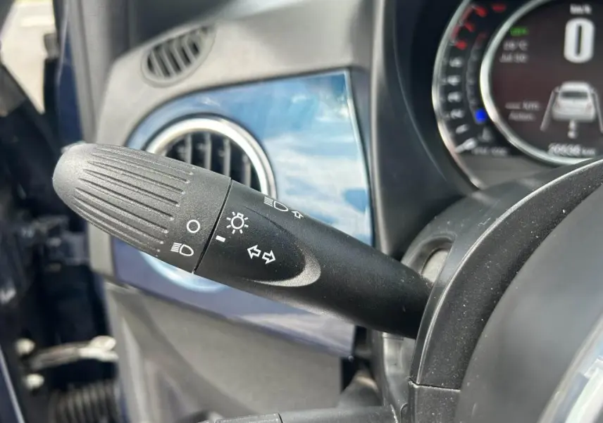 Gros plan sur la manette des clignotants et phares dans l'habitacle bleu d'une FIAT 500 2024 côté gauche.
