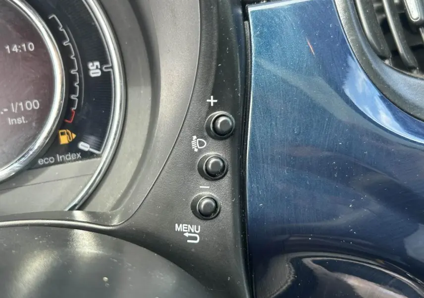 Détail des commandes d'éclairage et menu sur tableau de bord bleu du Fiat 500 2024 côté gauche.