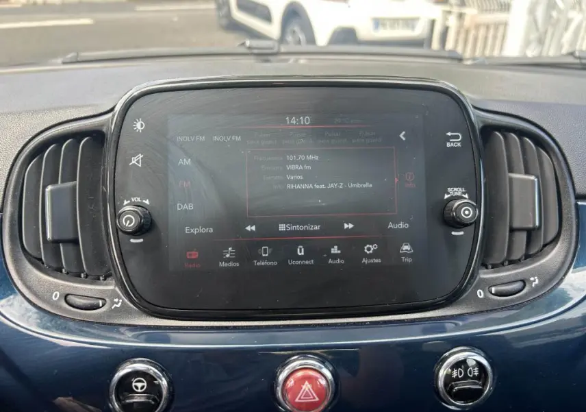 Vue rapprochée de l'écran tactile central du tableau de bord bleu d'une Fiat 500 2024 avec commandes audio et ventilation.