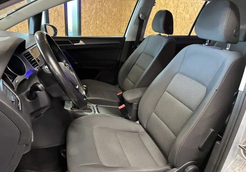 Vue intérieure côté conducteur d'une Volkswagen Golf Sportsvan 2019 avec sièges tissu gris et volant multifonction noir.