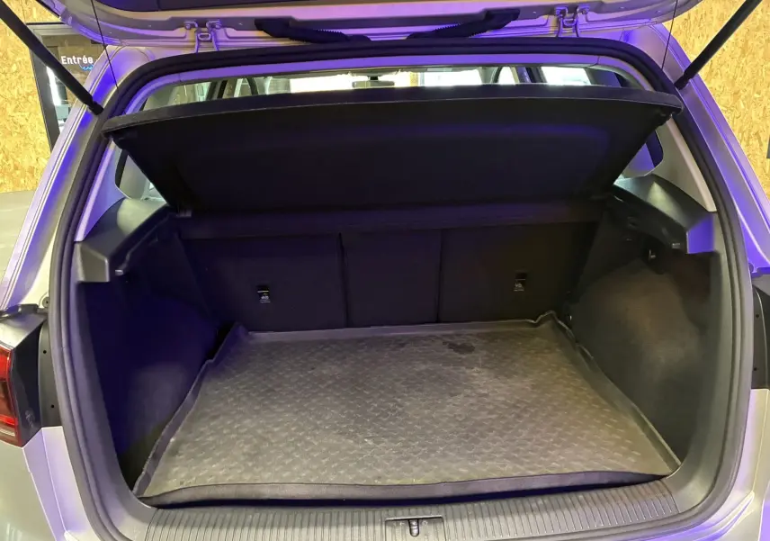 Coffre ouvert d’un Volkswagen Golf Sportsvan gris 2019, vue arrière montrant l’espace de chargement et la tablette cache-bagages.