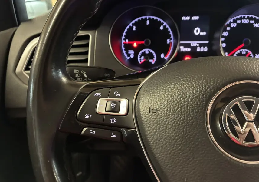 Gros plan sur le volant noir de la Volkswagen Golf Sportsvan 2019 avec commandes de régulateur et tableau de bord éclairé.