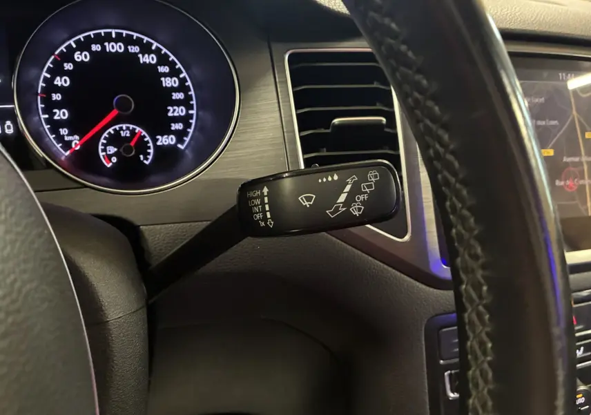 Gros plan sur la manette d’essuie-glace à gauche du volant dans l’habitacle gris-noir du Volkswagen Golf Sportsvan 2019.