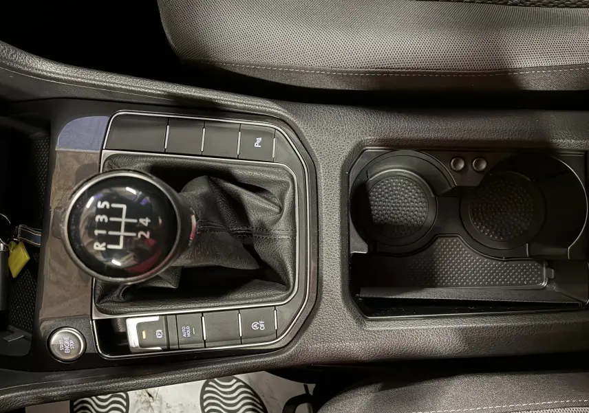 Gros plan sur la console centrale de la Volkswagen Golf Sportsvan grise, mettant en valeur le levier de vitesse manuel et les porte-gobelets.