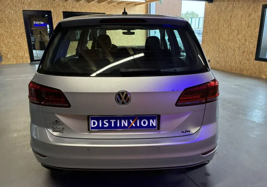Vue arrière d'un Volkswagen Golf Sportsvan gris 2019 avec logo distinctif et plaque d'immatriculation Distinxion.