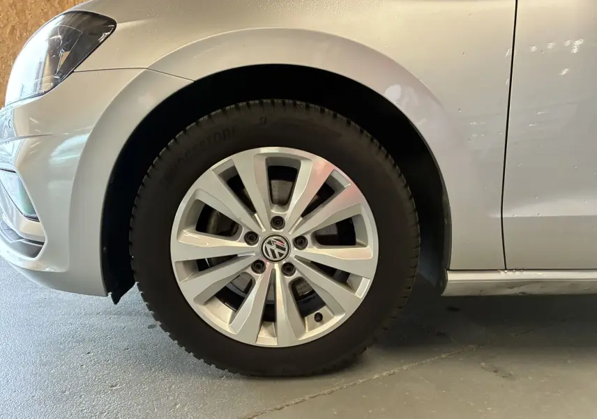 Gros plan sur la roue avant gauche grise d'une Volkswagen Golf Sportsvan 2019 avec jante alliage et logo VW central.