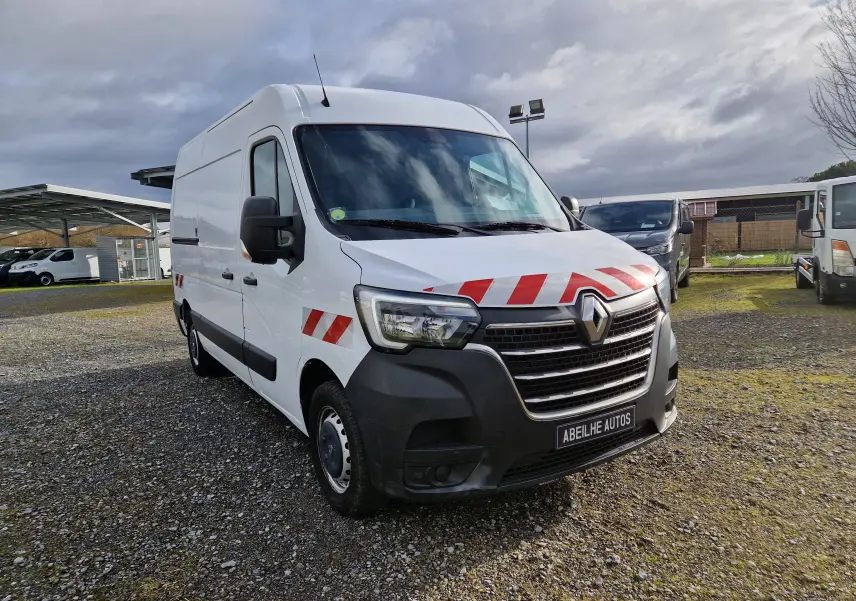 Vue 3/4 avant d’un Renault Master blanc avec bandes rouges réfléchissantes sur capot et porte côté gauche.