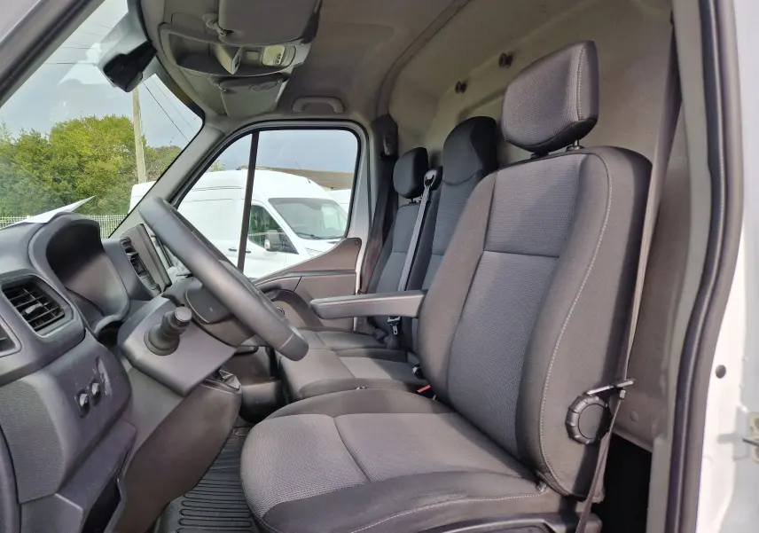 Vue intérieure côté conducteur du Renault Master blanc 2020, montrant les sièges gris et le volant avec commandes intégrées.