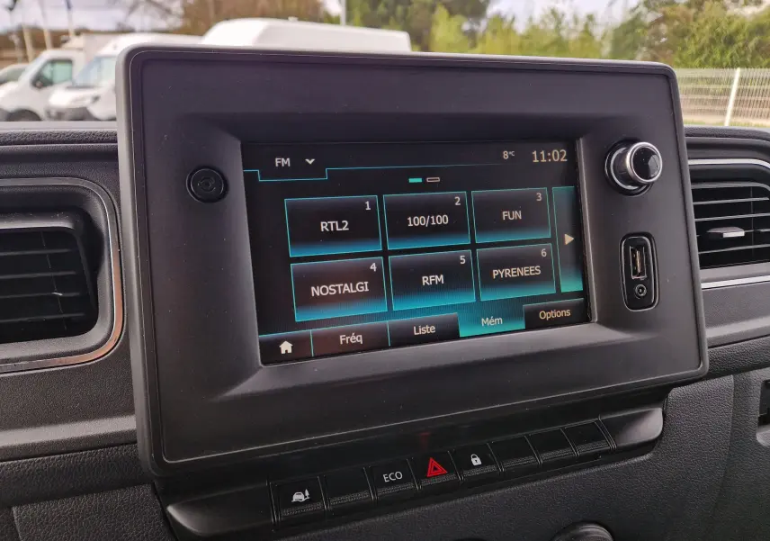 Gros plan sur l’écran tactile central du Renault Master blanc, affichant les stations radio avec commandes et prises USB visibles.