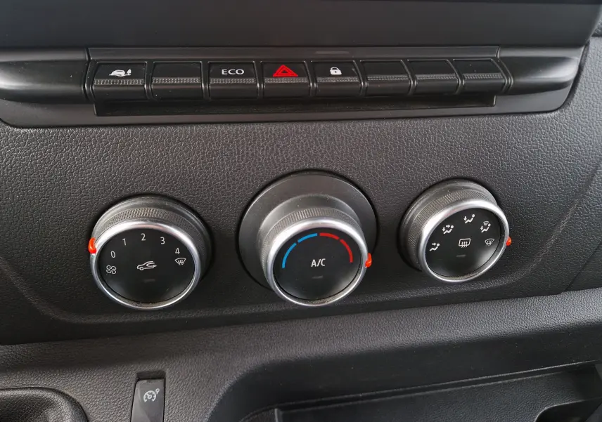 Gros plan sur les commandes de climatisation et boutons de fonction noirs du tableau de bord du Renault Master blanc 2020.