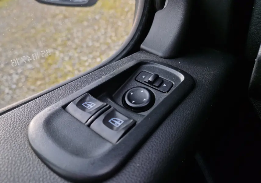Gros plan sur les commandes de lève-vitres et réglage des rétroviseurs côté conducteur du Renault Master blanc 2020.