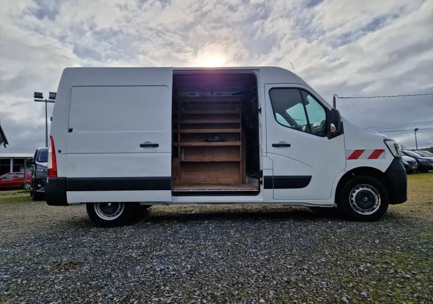 Vue latérale droite d’un Renault Master blanc 2020 avec porte coulissante ouverte révélant un aménagement bois intérieur.