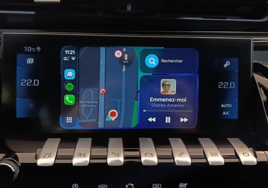 Écran tactile central du Peugeot 508 gris clair de 2020 affichant navigation et musique, avec commandes piano en dessous.