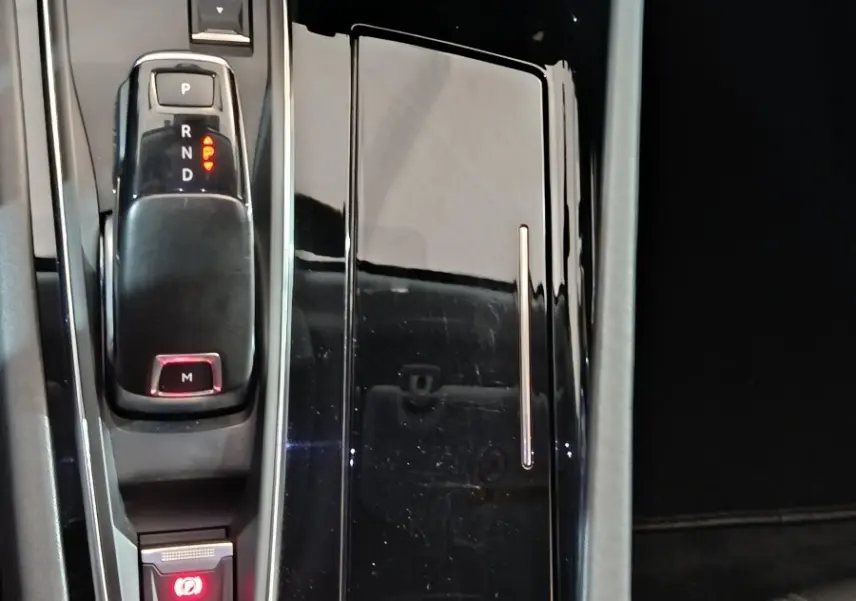 Vue rapprochée de la console centrale noire brillante du Peugeot 508 BlueHDi 130, avec levier de vitesses automatique et bouton start/stop.