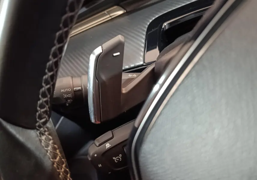 Gros plan sur les palettes au volant et commandes de clignotants du Peugeot 508 gris clair 2020, intérieur noir.