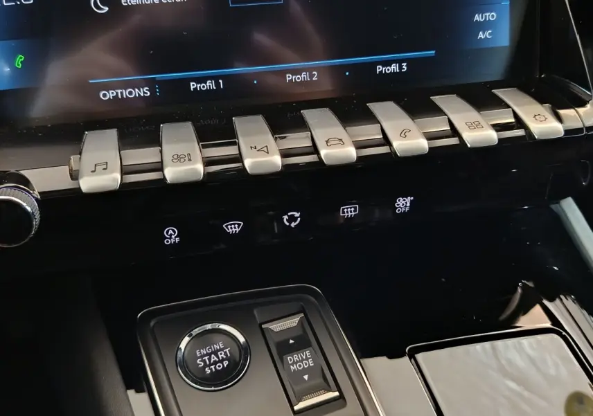 Gros plan sur la console centrale noire du Peugeot 508 gris clair, avec boutons de commande et bouton démarrage visible.