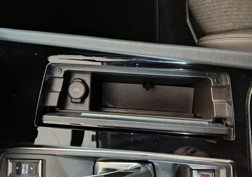 Gros plan sur la console centrale noire du Peugeot 508 gris clair, avec prise 12V et levier de boîte automatique.