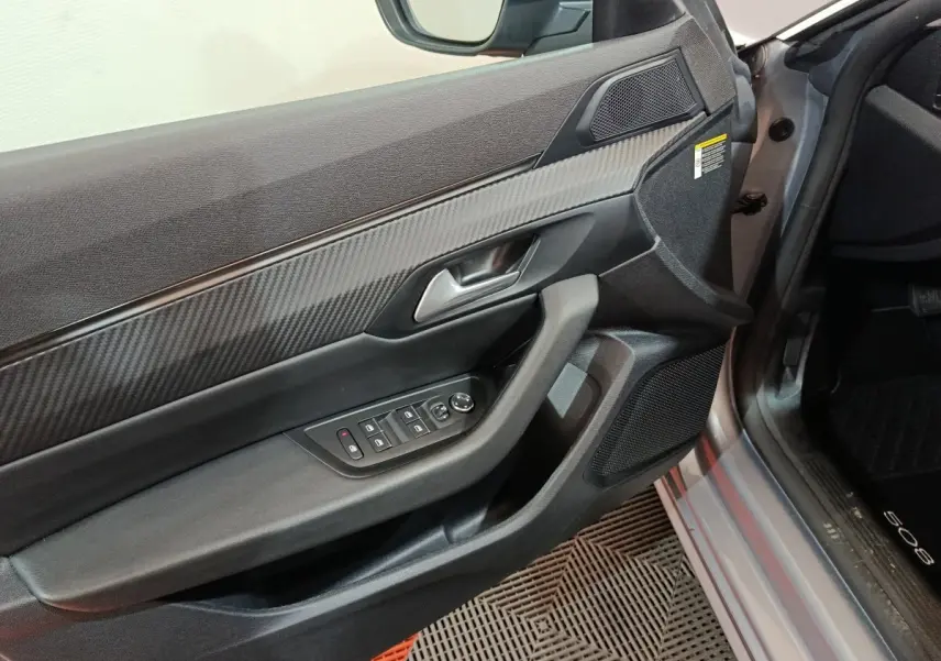 Vue rapprochée de la porte avant gauche gris clair du Peugeot 508 avec commandes électriques et habillage carbone.