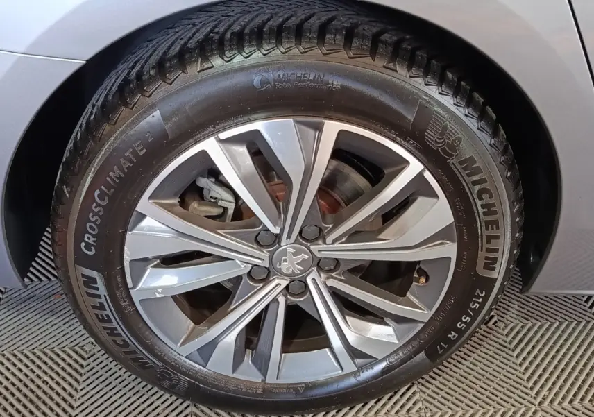Gros plan sur la roue avant droite gris clair de la Peugeot 508 avec jante alliage et pneu Michelin CrossClimate 2.
