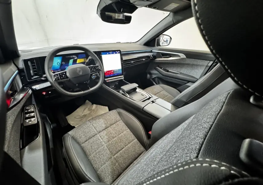 Intérieur Renault Espace 2025 vu côté conducteur, tableau de bord moderne avec écran tactile vertical et sièges tissu-cuir gris.