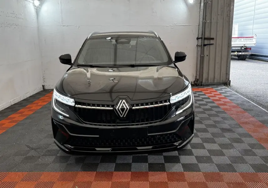 Vue frontale du Renault Espace noir 2025 avec calandre marquée et phares LED allumés dans un garage.