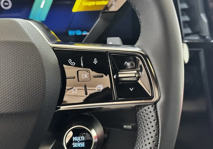 Gros plan sur les commandes gauche du volant cuir perforé du Renault Espace noir 2025 version techno hybride.