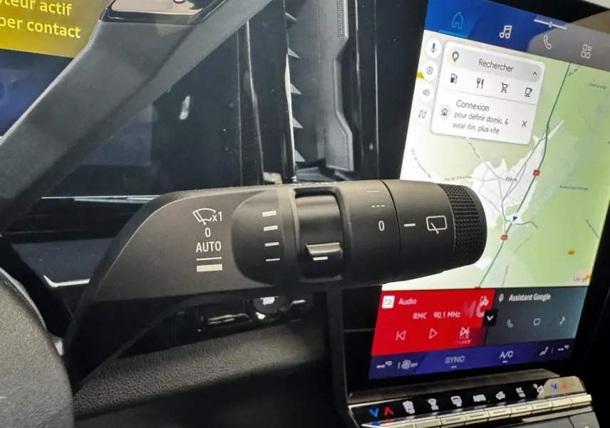 Gros plan sur la commande d’essuie-glace à gauche du volant, avec l’écran tactile central affichant la navigation du Renault Espace noir.