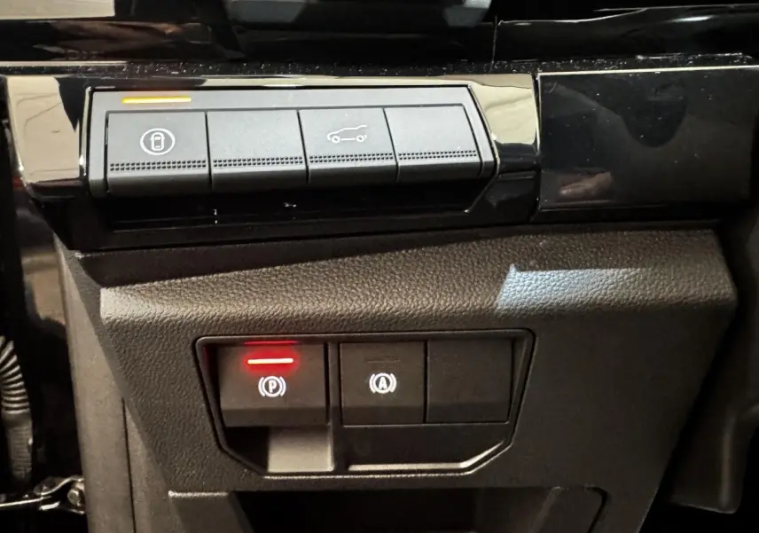 Gros plan sur les commandes du frein à main électrique et ouverture du coffre du Renault Espace noir 2025.