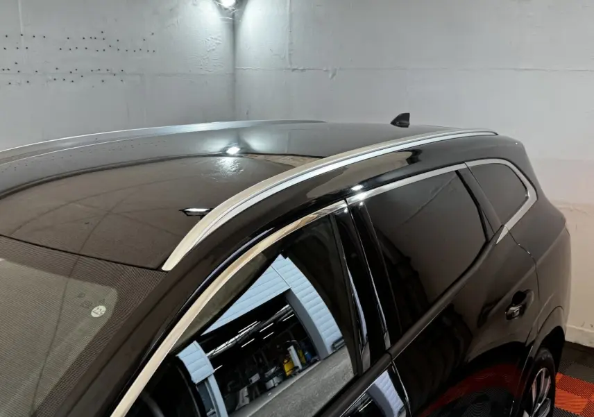 Vue en plongée du côté gauche arrière du Renault Espace noir avec rails de toit chromés et vitres teintées.