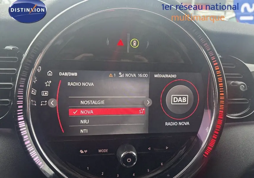 Affichage du système multimédia MINI 2023 en gros plan, avec sélection de la radio Nova sur écran circulaire lumineux.