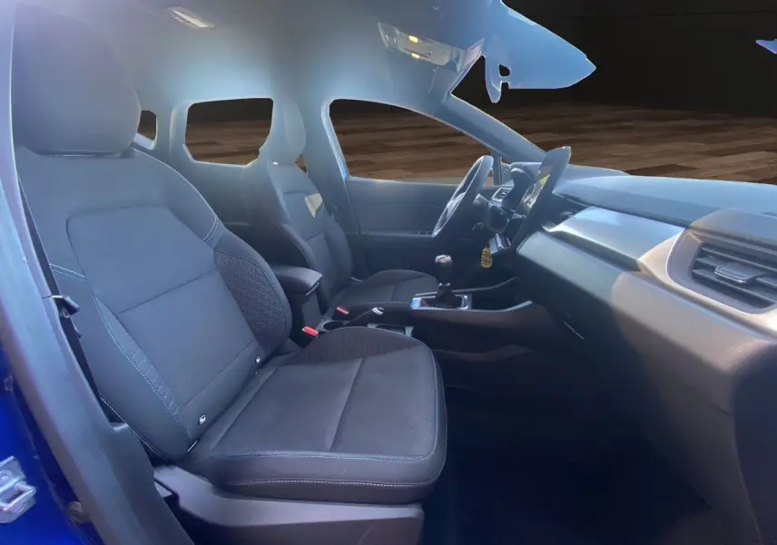 Intérieur avant du Renault Captur TCE 90 Evolution 2024, sièges noirs et tableau de bord avec boîte manuelle.